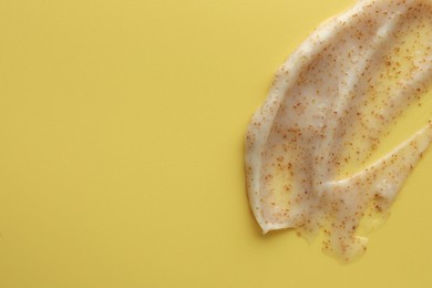 Sample of face scrub on yellow background, top view. Space for text