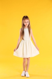 Full length portrait of cute little girl on yellow background
