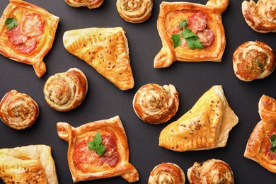 Photo of Various delicious puff pastry with tasty filling on black background, flat lay