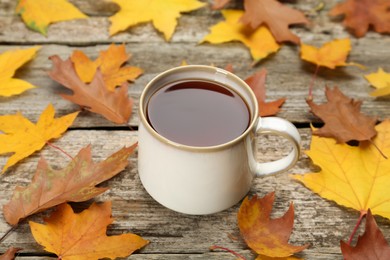 Cup of hot tea and autumn leaves on wooden table