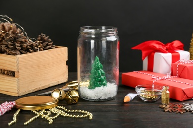 Composition of instruments and materials for snow globe on black wooden table