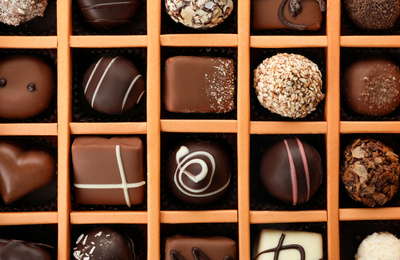 Box with different chocolate candies as background, top view
