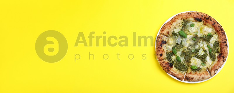 Delicious pizza with pesto, cheese and basil on yellow background, top view with space for text. Banner design