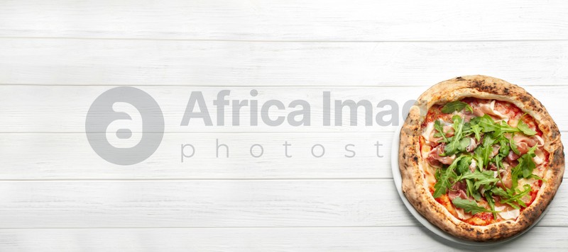Tasty pizza with meat and arugula on white wooden table, top view with space for text. Banner design