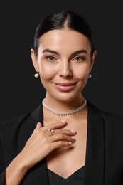 Young woman with elegant pearl jewelry on black background