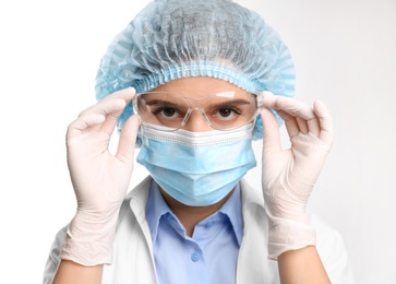Doctor with medical gloves, mask, cap and protective goggles on white background