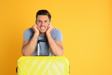 Handsome man with suitcase for summer trip on yellow background. Vacation travel