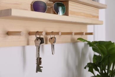 Wooden hanger for keys on white wall, closeup
