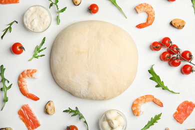 Flat lay composition with dough and fresh ingredients for seafood pizza on white table