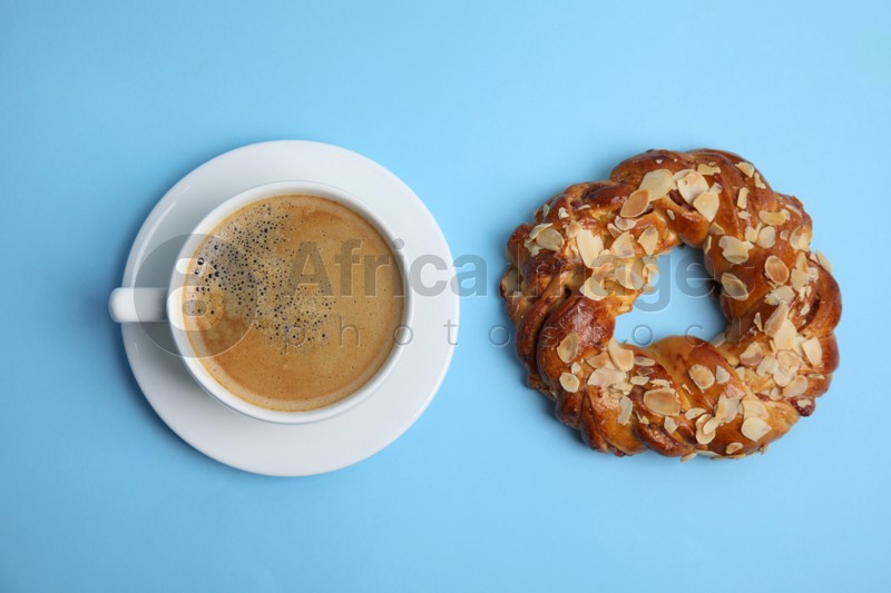 Photo of Delicious coffee and pastry on light blue background, flat lay