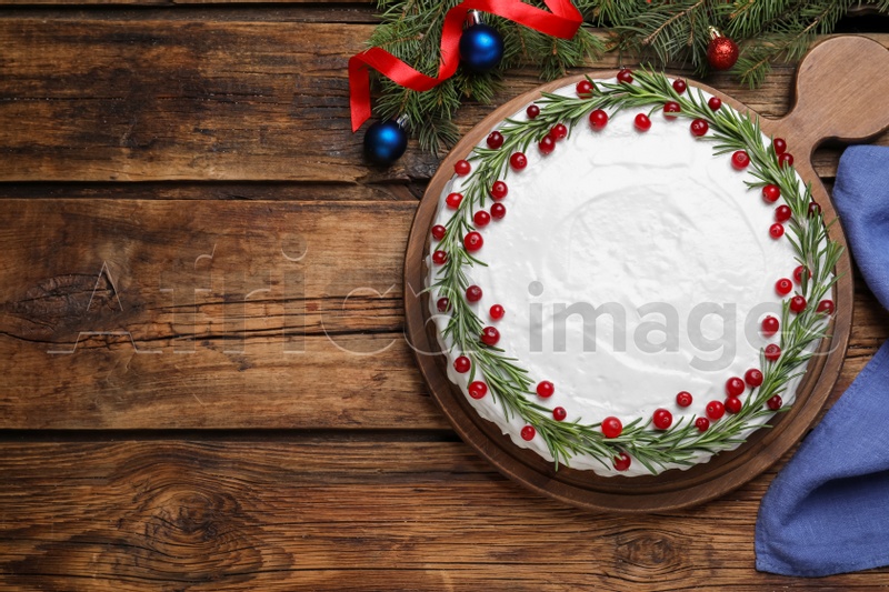 Photo of Traditional Christmas cake decorated with rosemary and cranberries on wooden table, flat lay. Space for text