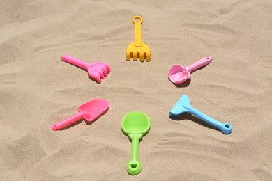 Photo of Bright plastic rakes and shovels on sand. Beach toys