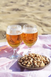 Photo of Glasses of cold beer and pistachios on sandy beach
