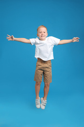 Cute little boy jumping on light blue background