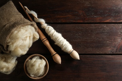 Soft wool and spindles on white wooden table, flat lay. Space for text