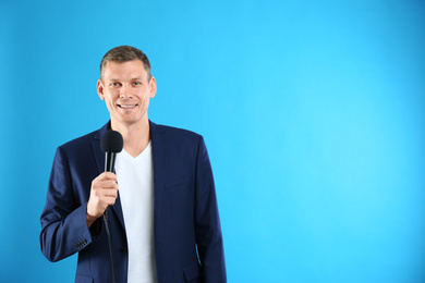 Male journalist with microphone on blue background. Space for text