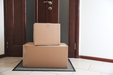 Cardboard boxes on rug near door. Parcel delivery service