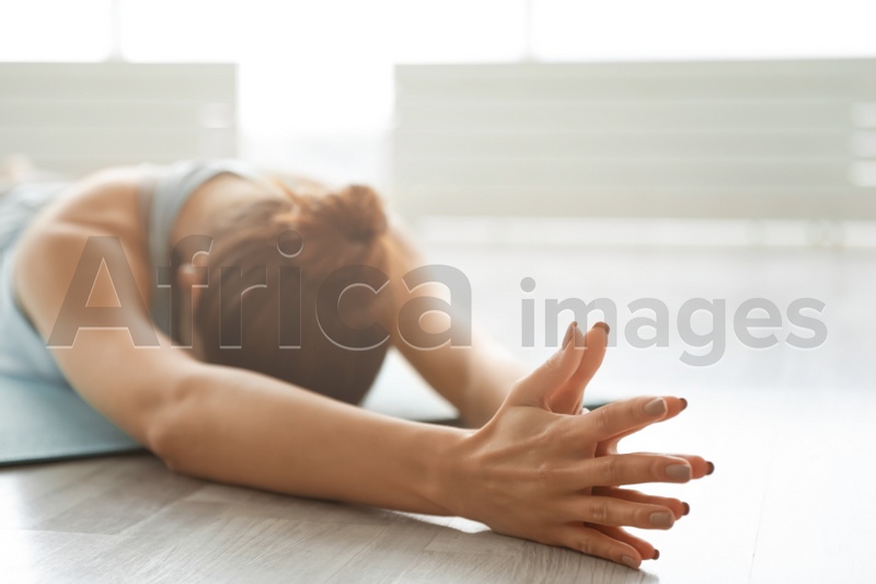 Young woman practicing extended child's asana pose in yoga studio. Utthita Balasana