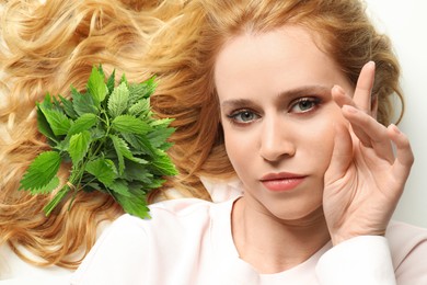 Image of Natural hair care. Beautiful young woman and green stinging nettles on white background, top view