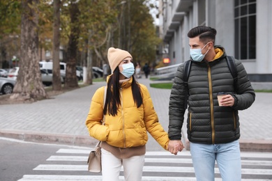 Couple in medical face masks walking outdoors. Personal protection during COVID-19 pandemic