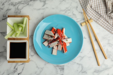Photo of Fresh crab sticks with soy sauce and celery served on white marble table, flat lay