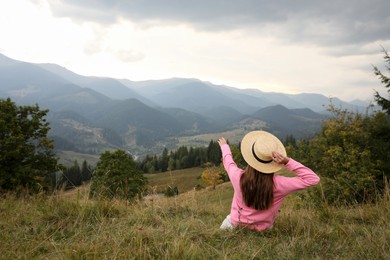 Photo of Young woman enjoying beautiful mountains landscape, back view. Space for text