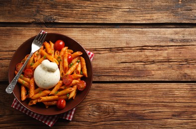 Delicious pasta with burrata cheese and tomatoes on wooden table, top view. Space for text