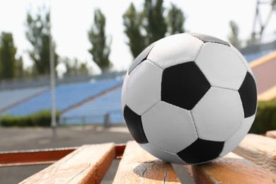 Football ball on wooden bench in stadium