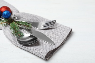Cutlery, napkin and Christmas decor on wooden table, closeup. Festive table setting