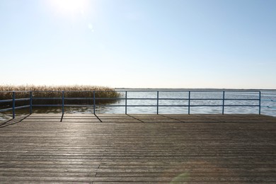 Beautiful view of wooden terrace with railing near river on sunny day