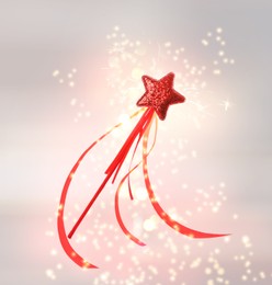 Beautiful red wand and shiny magical dust on light background