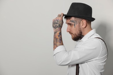 Photo of Handsome hipster man wearing hat on light grey background. Space for text