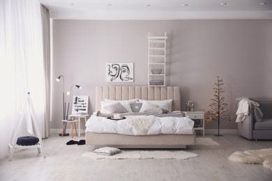 Cozy bedroom interior with decorative tree and beautiful pictures