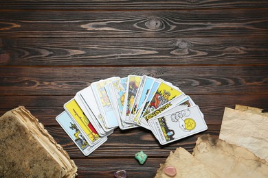 Tarot cards, old book and crystals on wooden table, flat lay