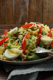 Delicious salad with Chinese cabbage and quail eggs served on wooden table, closeup