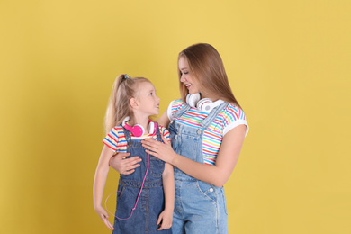 Happy mother and little daughter on yellow background