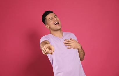 Handsome man laughing on pink background. Funny joke