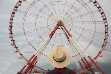 Teenage boy near large Ferris wheel outdoors