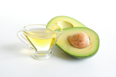 Gravy boat with oil and ripe fresh avocado on white background