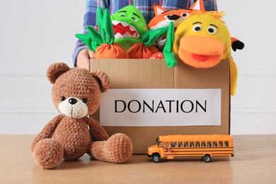 Little boy holding donation box with toys against white background, closeup
