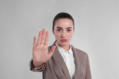 Woman in suit showing gesture stop on light grey background