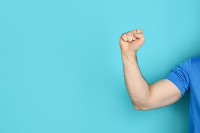 Young man showing clenched fist on color background. Space for text