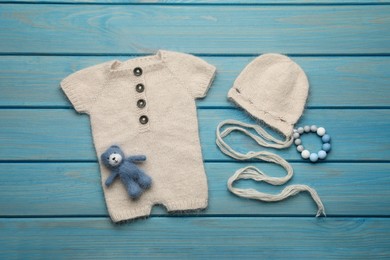 Flat lay composition with cute baby knitwear for photoshoot on light blue wooden background