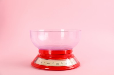 Kitchen scale with plastic bowl on pink background