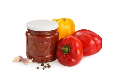 Photo of Glass jar of delicious canned lecho, fresh vegetables and peppercorns on white background