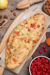 Unbaked Stollen with candied fruits and raisins on wooden table, flat lay