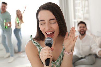 Young woman singing karaoke with friends at home