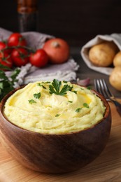 Photo of Bowl of freshly cooked mashed potatoes with parsley served on wooden table