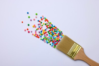 Photo of Brush painting with colorful sprinkles on light background, top view. Creative concept
