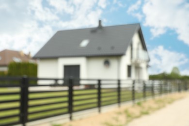 Blurred view of suburban street with beautiful house behind fence